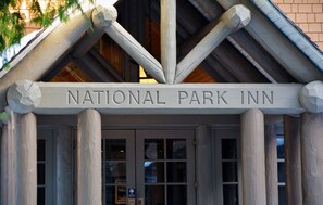La entrada al National Park Inn, con un cartel sobre las puertas y columnas de madera.