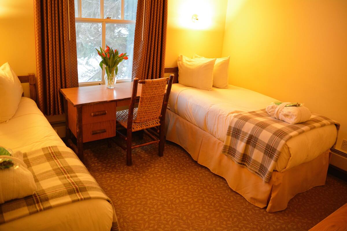Ett hotellrum med två sängar, ett skrivbord och en stol.