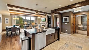 Una cocina moderna con una isla central, vigas de madera y un comedor con vistas.