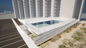 A modern building with a rectangular pool in the center, surrounded by a white fence.