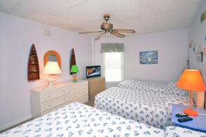 A bedroom with two beds, a ceiling fan, a TV, and a dresser.