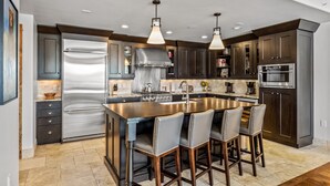 A modern kitchen with a stainless steel refrigerator, double sink, and bar stools.
