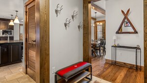 A modern kitchen with wooden beams, a dining area with a wooden table, and a bench with a red cushion.