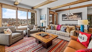 A spacious living room with large windows, a wooden ceiling, and a variety of seating options.