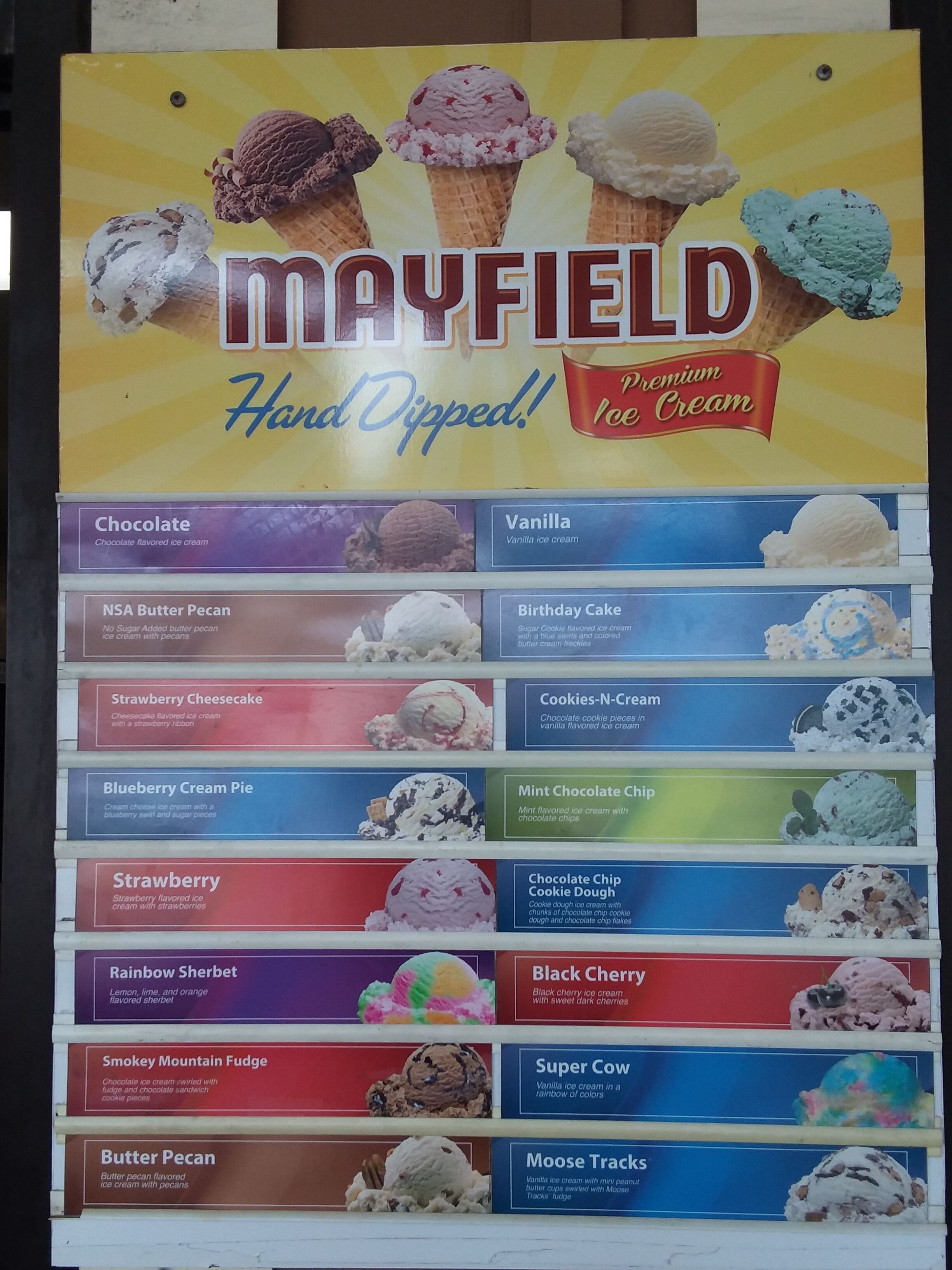 Un panneau affichant le menu de Mayfield Hand Dipped Premium Ice Cream, avec une liste des différentes saveurs proposées.