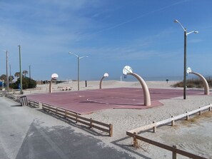 Una cancha de baloncesto al aire libre con dos canastas, rodeada de arena y barreras de madera.