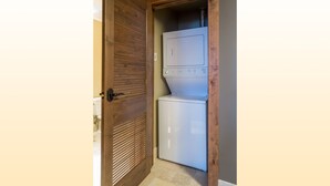 A laundry room with a built-in washer and dryer, wooden door, and tiled floor. - Edgemont 2504 Luxury On Mountain Condo With Ski-In/Ski-Out Access! (Steamboat Springs)