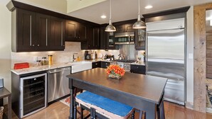 A modern kitchen with dark cabinets, stainless steel appliances, and a central island with a vase of flowers. - Edgemont 2504 Luxury On Mountain Condo With Ski-In/Ski-Out Access! (Steamboat Springs)