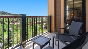A balcony with a view of a green landscape and a building in the background. - Edgemont 2504 Luxury On Mountain Condo With Ski-In/Ski-Out Access! (Steamboat Springs)