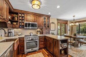 A kitchen with wooden cabinets, a stainless steel microwave, and a built-in oven. - Bear Claw 301 Exceptional On Mountain Condo With Ski-In/Ski-Out Access! (Steamboat Springs)