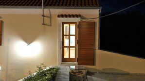 A building with a tiled roof, a wooden door, and a light fixture on the wall. - Aunt Regina House, authentic house from 1882. with magnificent see view (Božava)
