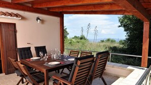 A wooden dining table set for six with chairs, a view of the outdoors, and a door with a traditional design. - Aunt Regina House, authentic house from 1882. with magnificent see view (Božava)