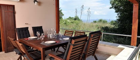 A wooden dining table set for six with chairs, a view of the outdoors, and a door with a traditional design.