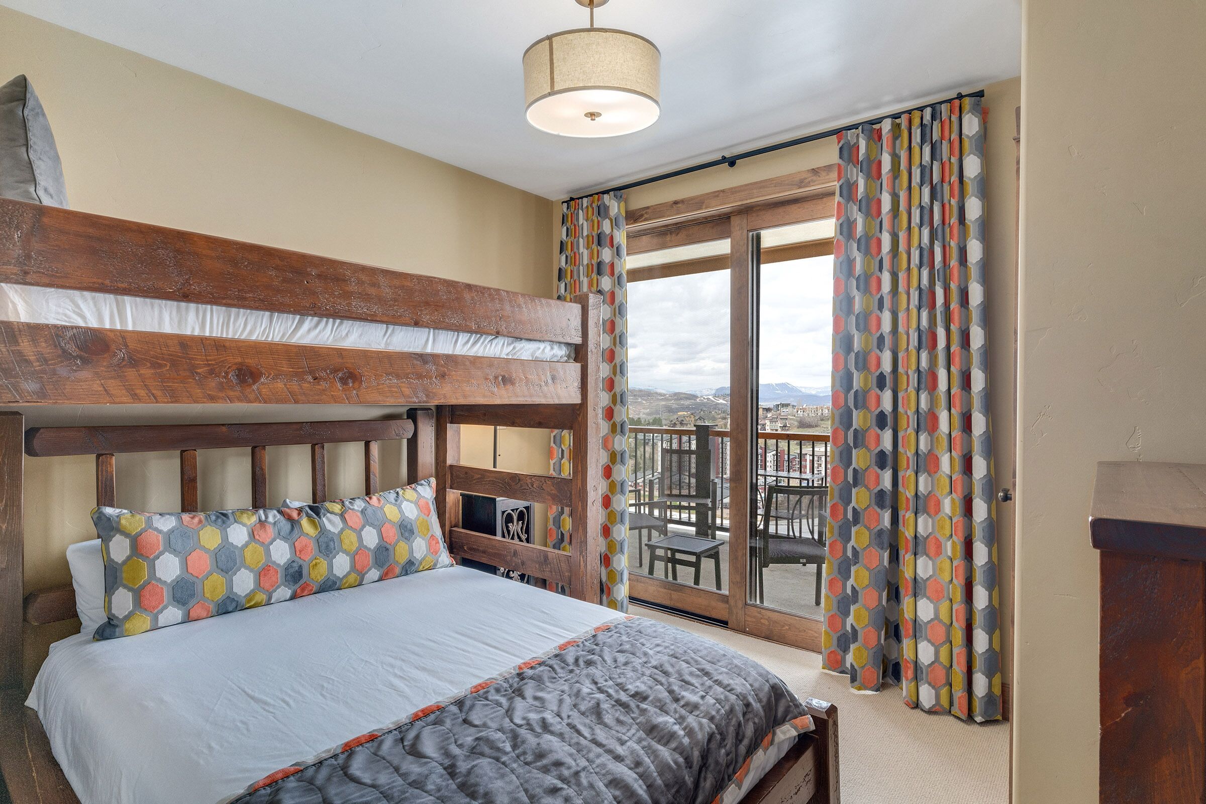 Une chambre avec un lit superposé, un balcon avec vue et un rideau à motifs.