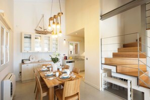 A modern kitchen with white cabinetry, a dining table set for four, and a staircase with a metal railing.