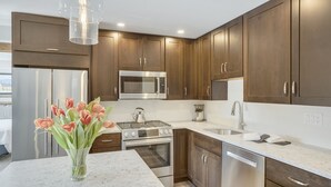 A modern kitchen with wooden cabinets, stainless steel appliances, and a marble countertop. - Bear Claw 302 Premium On Mountain Condo With Ski-In/Ski-Out Access! (Steamboat Springs)
