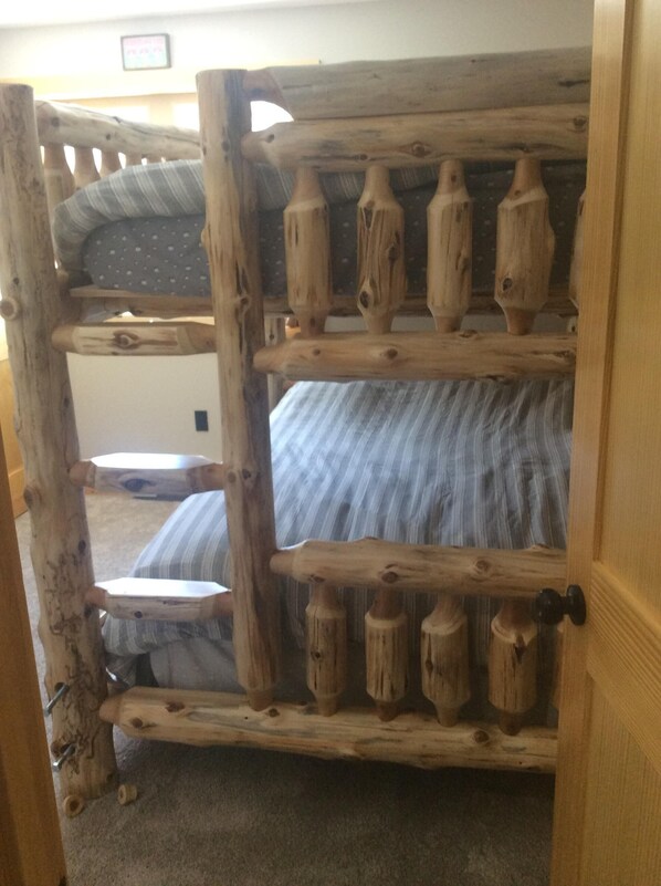 A bunk bed with a wooden frame and a striped mattress.