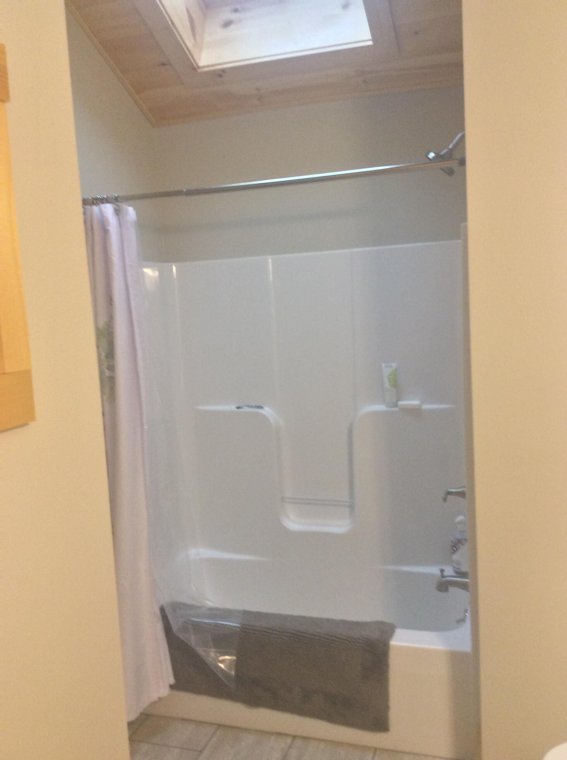 A shower with a glass door, a bathtub, and a skylight above.