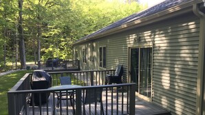 A deck with outdoor furniture, a covered grill, and a sliding glass door to a house.