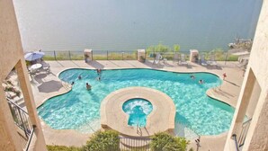 Ein Poolbereich mit mehreren Schwimmbecken, einem Whirlpool und Blick auf einen See.