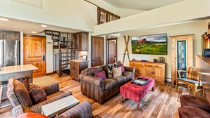 A spacious living area with a wooden staircase, a large sofa set, a dining table, and a kitchen area. - Bear Claw 404 Premium On Mountain Condo With Ski-In/Ski-Out Access! (Steamboat Springs)