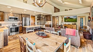 A spacious kitchen with modern appliances, a dining area with a wooden table, and a cozy living room with a fireplace. - Bear Claw 404 Premium On Mountain Condo With Ski-In/Ski-Out Access! (Steamboat Springs)