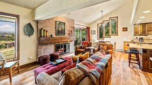 A spacious living room with a fireplace, comfortable seating, and a view of the outdoors. - Bear Claw 404 Premium On Mountain Condo With Ski-In/Ski-Out Access! (Steamboat Springs)