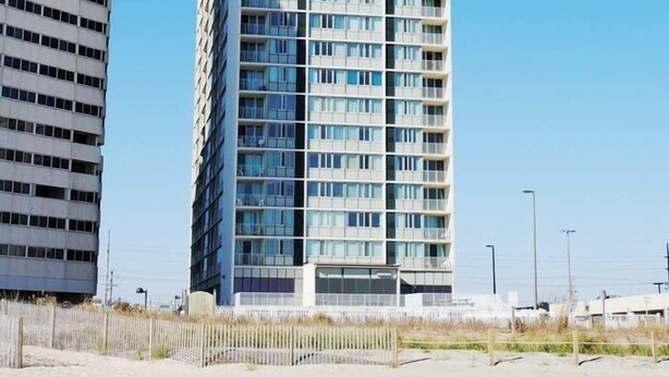 A tall, modern building with a glass facade and multiple balconies.