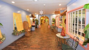A corridor with a brick floor, wicker chairs, potted plants, and a sign for 'Quay Store'.