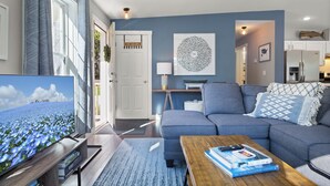 A modern living room with a grey sofa, a coffee table, and a TV on a wooden stand.