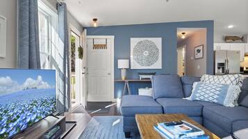 A modern living room with a grey sofa, a coffee table, and a TV on a wooden stand.