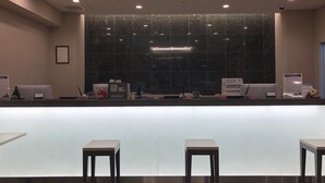 A reception desk with a large window, two chairs, and a sign indicating a front desk area.
