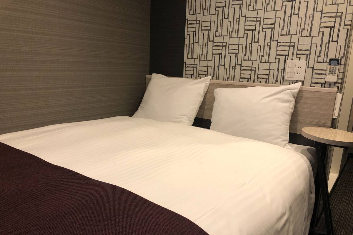 Una habitación de hotel con una cama grande, una mesita redonda y un papel tapiz estampado.