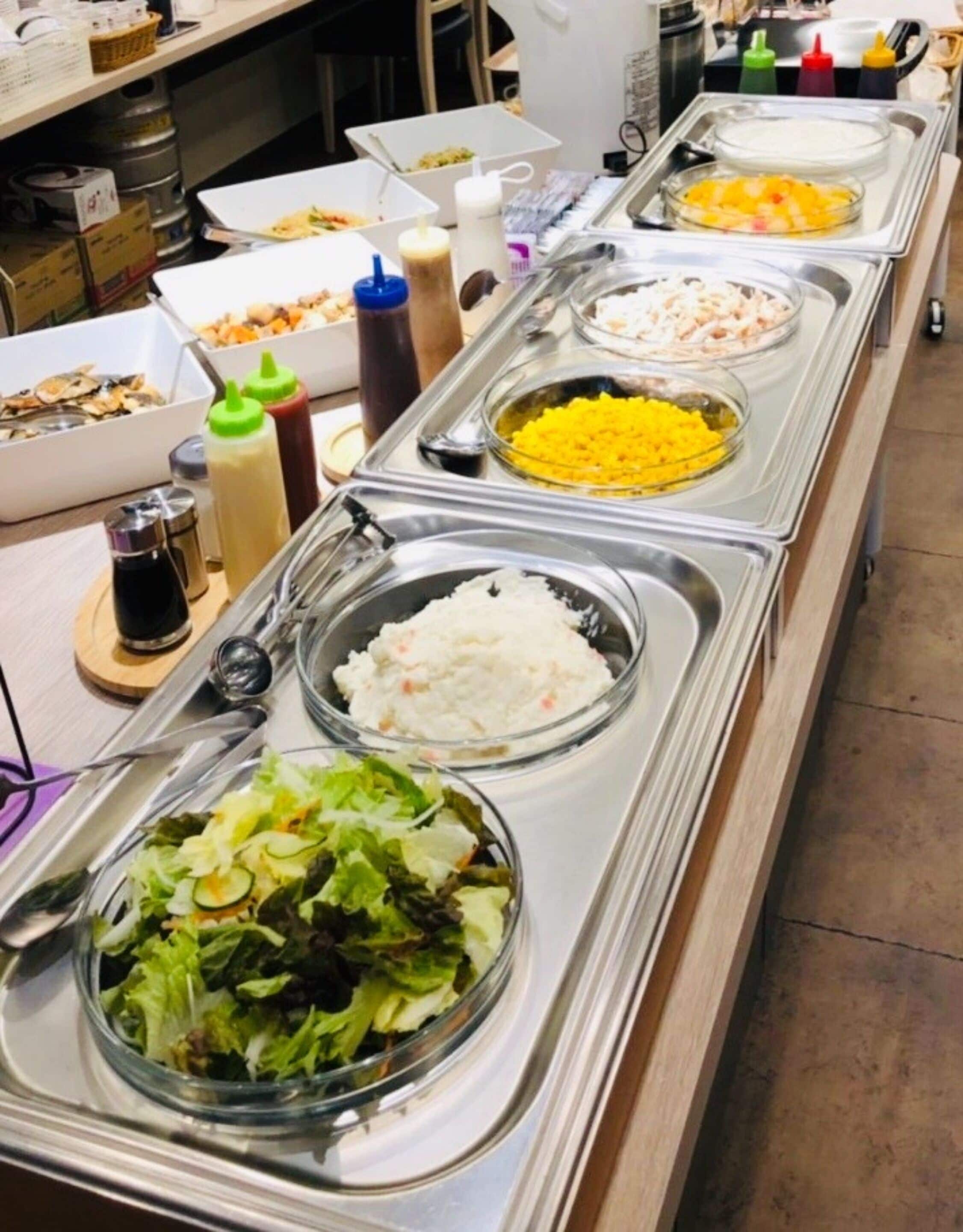 A buffet line with various food items including rice, salad, and other dishes.
