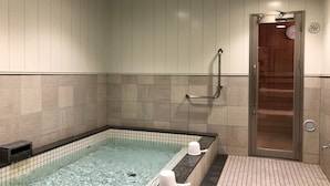 A spa area with a glass-bottomed hot tub, a wooden door, and a tiled floor.