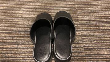 A pair of black slippers on a textured carpet.