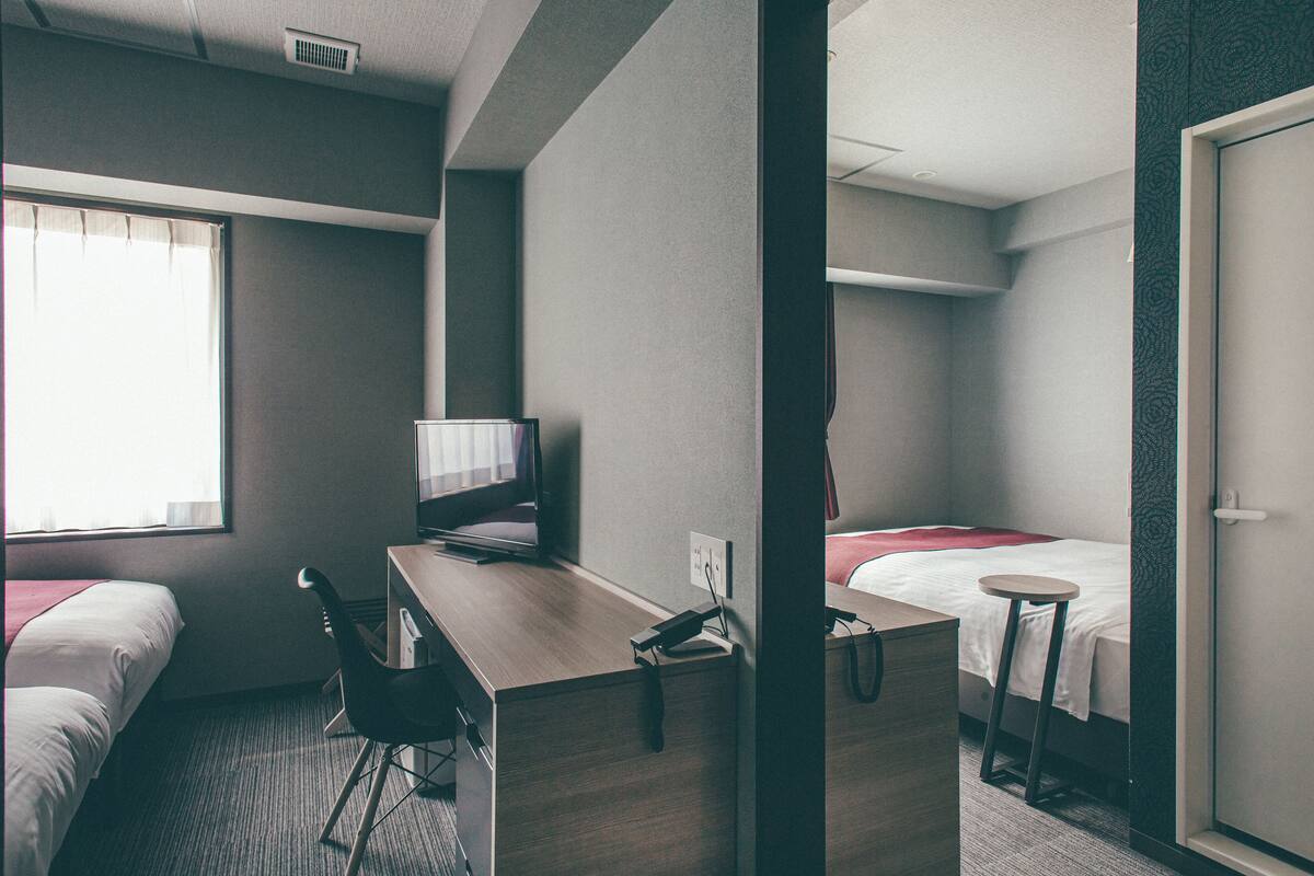Habitación de hotel con escritorio, dos camas, una silla y televisión.