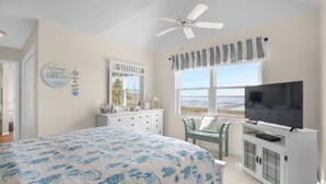 Un dormitorio con una cama grande, televisor, cómoda y ventana con vistas.