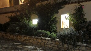 A stone-paved courtyard with a stone wall and various shrubs and plants.