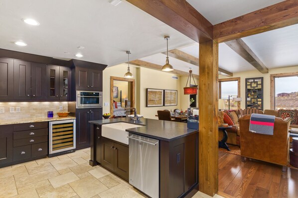 A modern kitchen with dark cabinetry, a central island, and a dining area with a view.