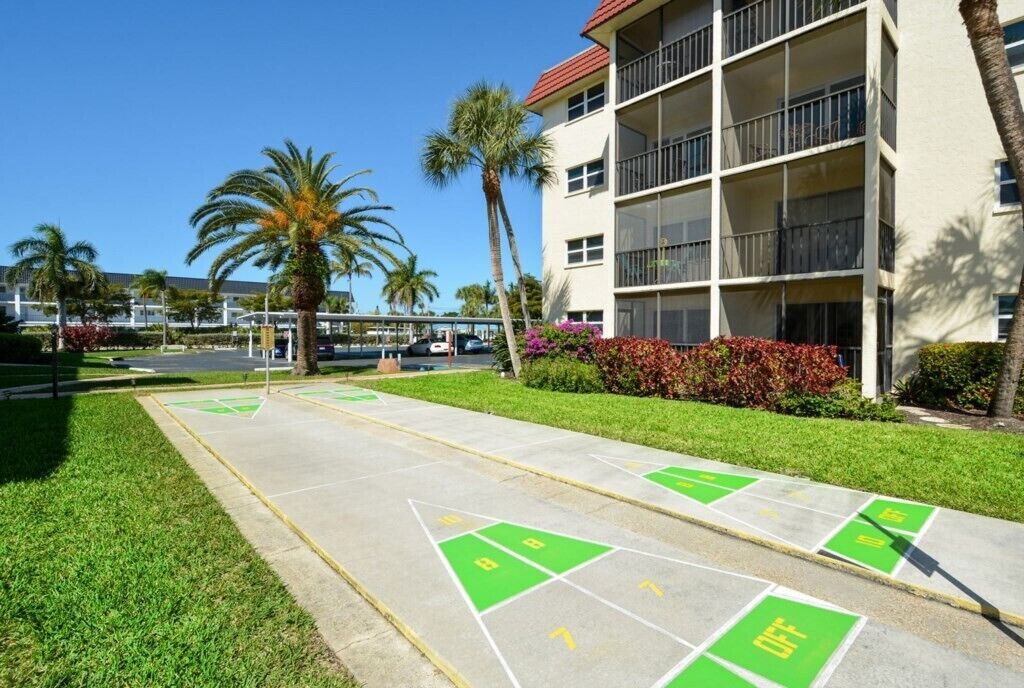 Ein Innenhof mit einem Shuffleboardplatz, Palmen und einem Gebäude mit Balkonen.