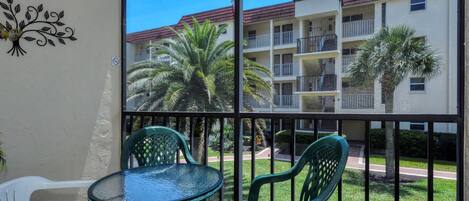 A balcony with a glass door, a round table, and two chairs.
