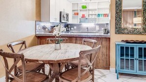 Une cuisine compacte dotée d’un îlot central, de meubles blancs et d’un meuble bleu.