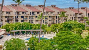 Un hotel con varios balcones, una piscina y abundante vegetación.