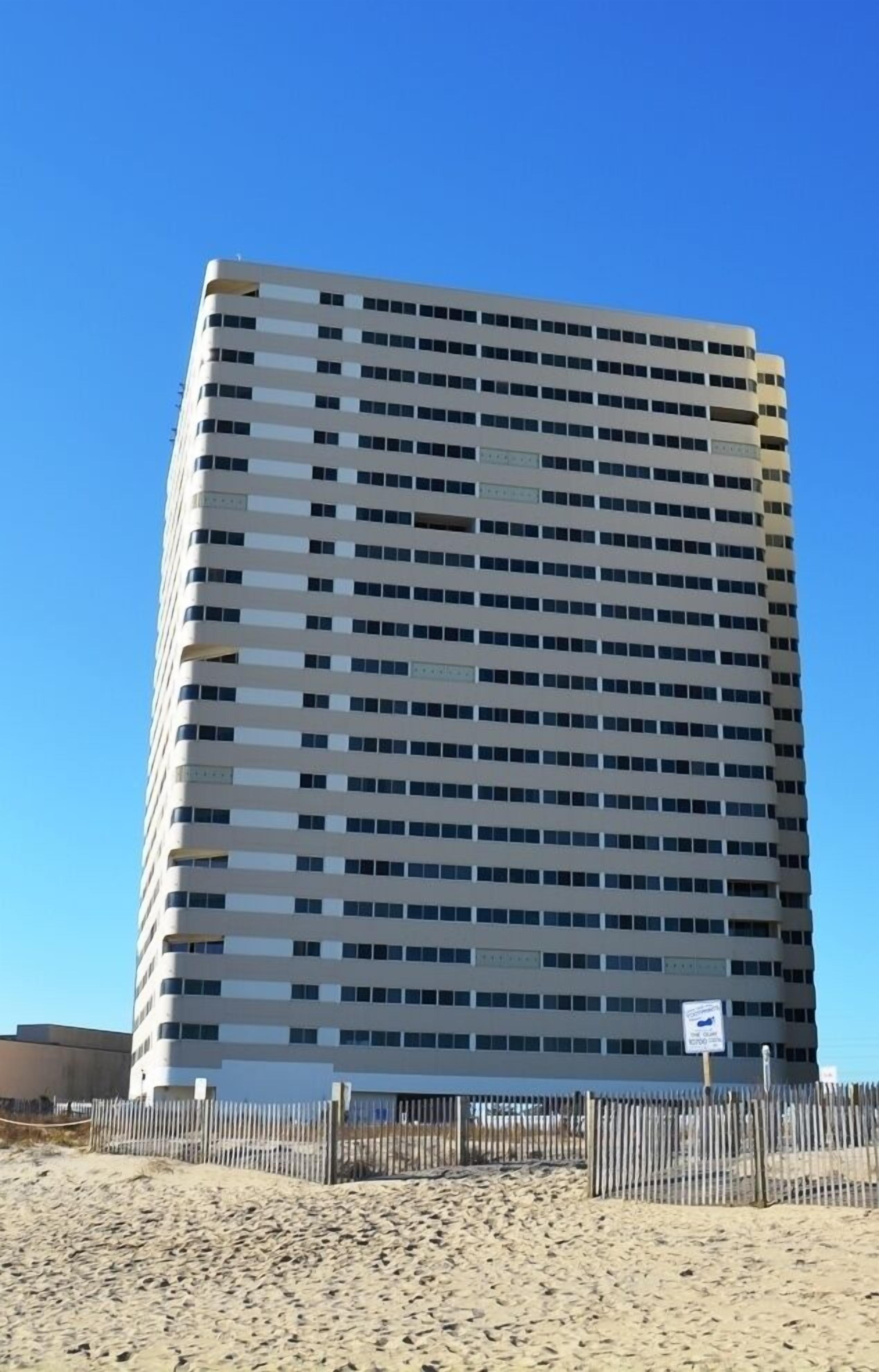 Un grand bâtiment rectangulaire, doté d’une façade à fenêtres disposées en réseau, d’un toit plat et d’une enseigne indiquant qu’il s’agit d’un hôtel.