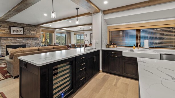 Una cocina moderna con gabinetes oscuros, una isla grande y una pared de acento de piedra.