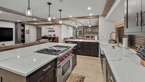 Una cocina moderna con una isla grande, muebles oscuros y electrodomésticos de acero inoxidable.
