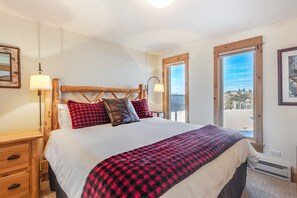Cozy bedroom with a large bed, wooden nightstand, and a picture on the wall, offering a view of the outside.