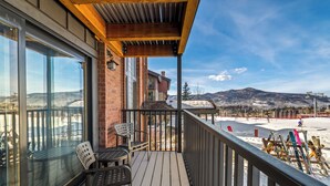 A wooden deck with a glass door leading to a patio area. - Bear Claw 103 Mountain Condo With Ski-In/Ski-Out Access! (Steamboat Springs)