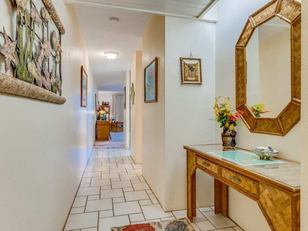 A hallway with a wooden console table, a mirror, and a vase of flowers.